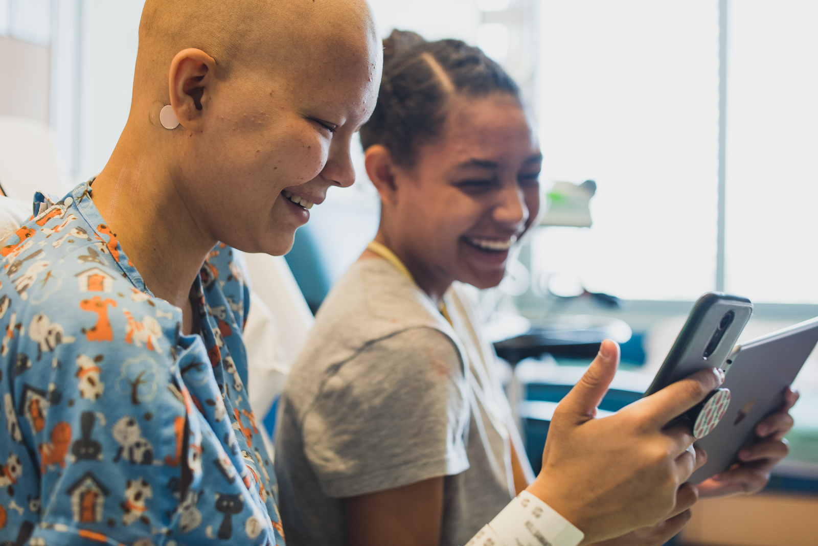 Two young patients playing together on a tablet.